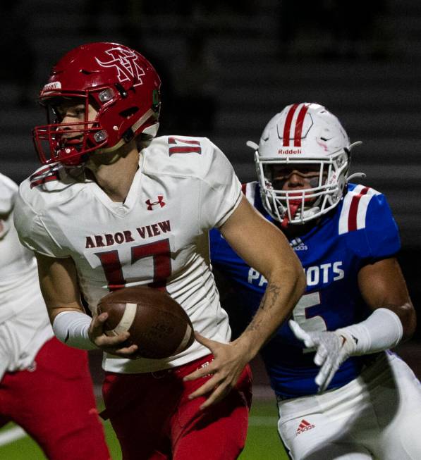 Arbor View High quarterback Kyle Holmes (17) chased by Liberty High defensive end Anthony Jones ...