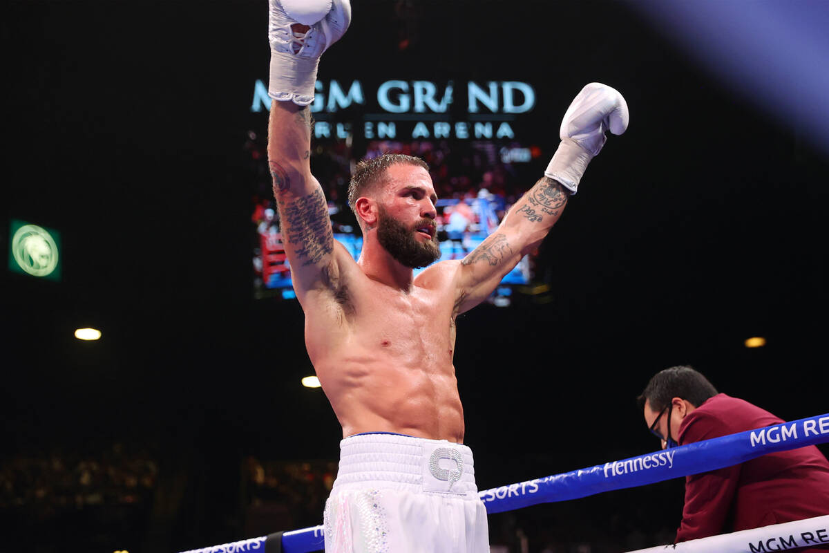 Caleb Plant raises his arms as he walks to his corner at the end of the ninth round of a super ...