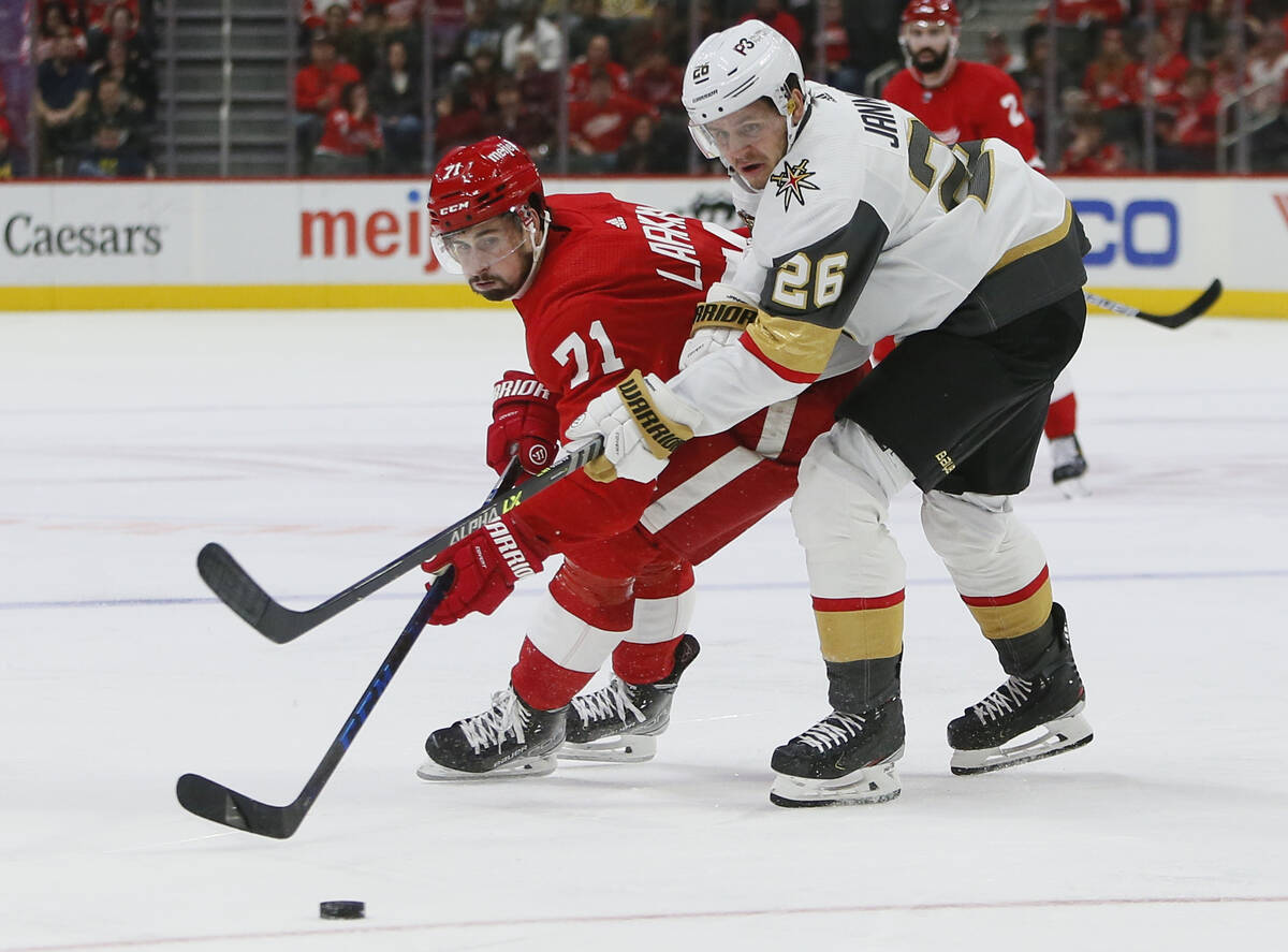 Detroit Red Wings center Dylan Larkin (71) is held off the puck by Vegas Golden Knights center ...