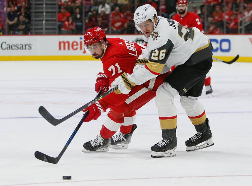 Detroit Red Wings center Dylan Larkin (71) is held off the puck by Vegas Golden Knights center ...