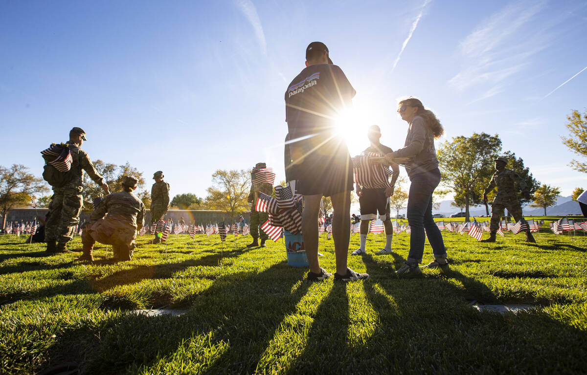 Volunteers place American flags on graves at the Southern Nevada Veterans Memorial Cemetery in ...