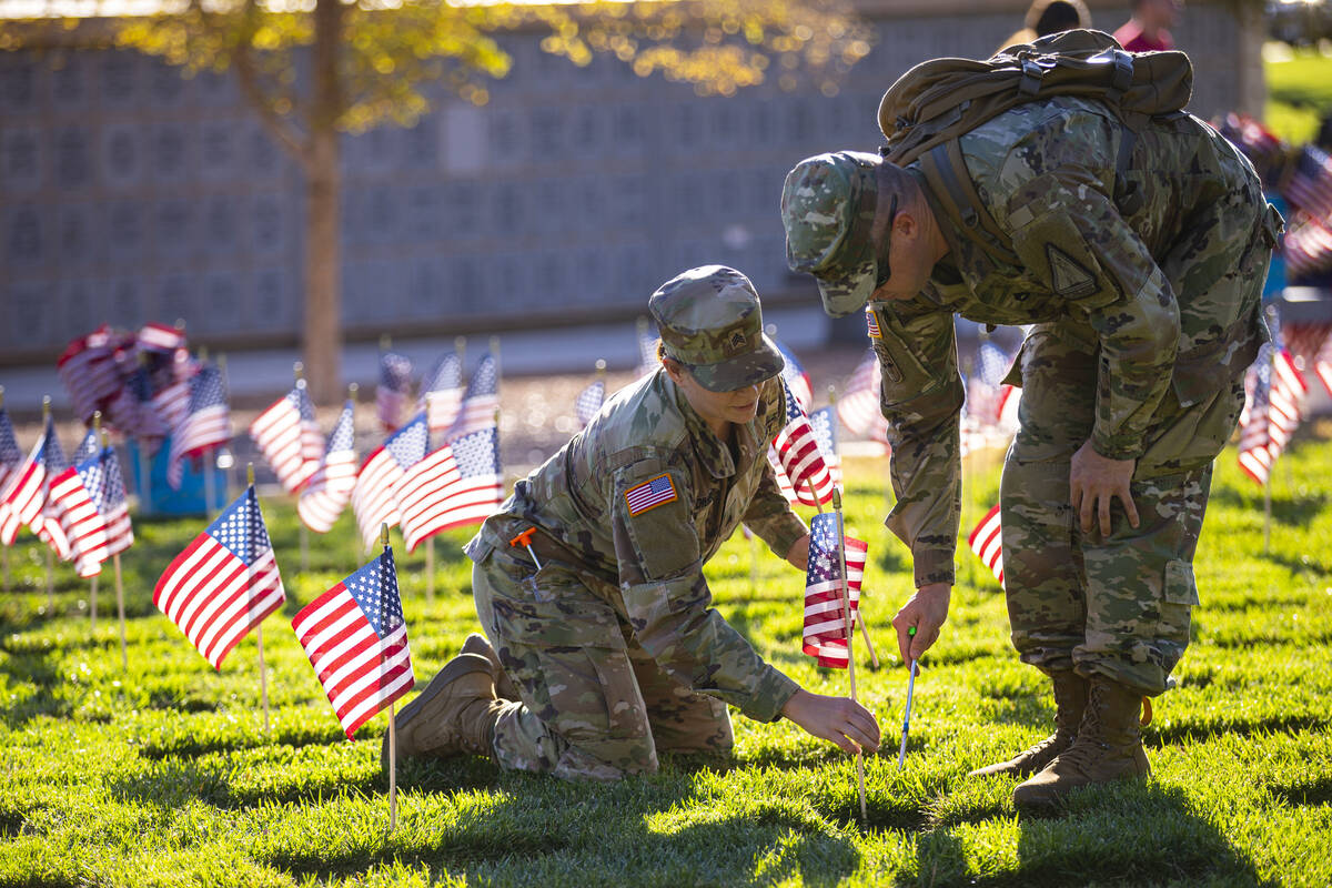Nevada Army National Guard Sgt. April DiLiberto, left, and SFC John Foley place American flags ...