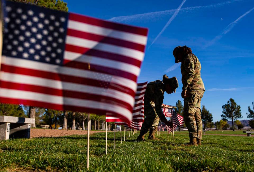 Air Force Senior Airmen Shakira Jefferson, left, and Kayla Stephens place American flags on gra ...