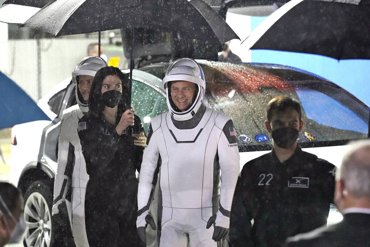 NASA astronaut Tom Marshburn, center, smiles as he stands under an umbrella after leaving the O ...
