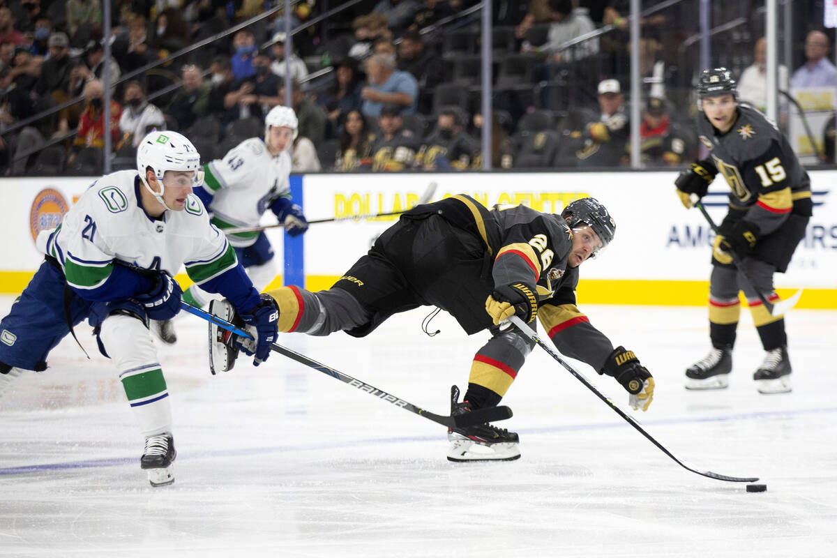 Golden Knights center Mattias Janmark (26) loses control of the puck as Canucks left wing Nils ...