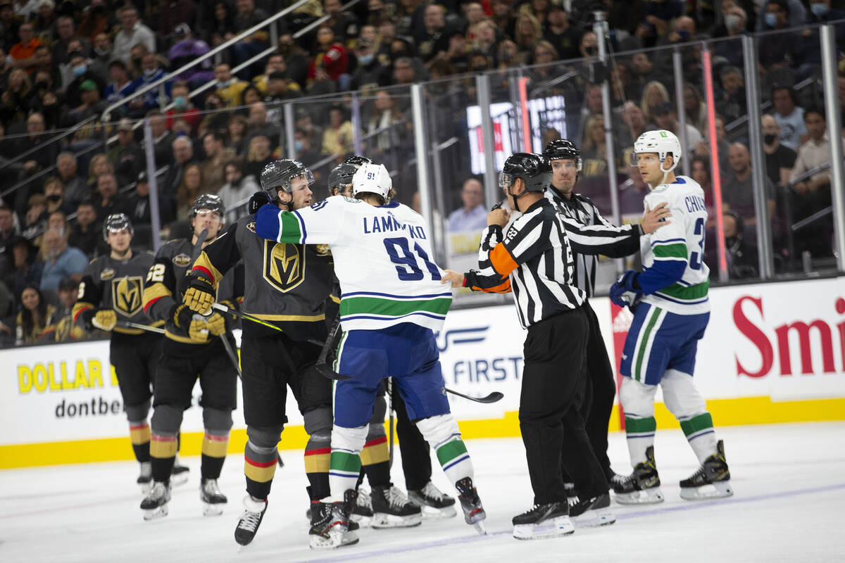 Referees pull apart Golden Knights center Brett Howden (21) and Canucks right wing Alex Chiasso ...