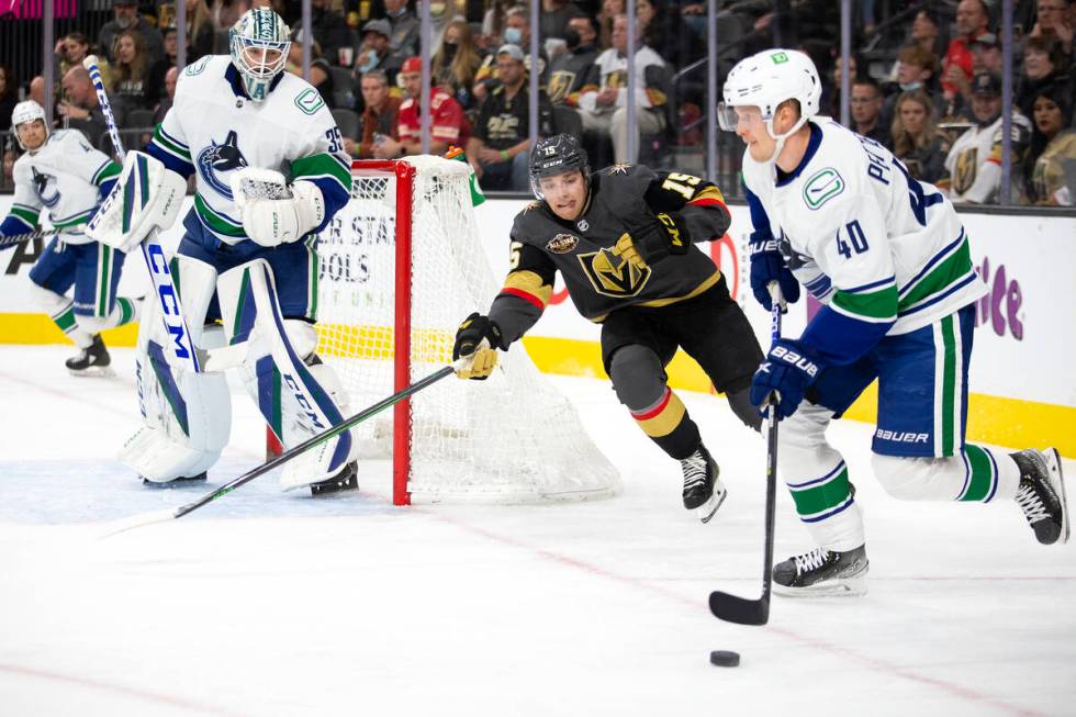 Golden Knights center Jake Leschyshyn (15) reaches for the puck while Canucks center Elias Pett ...