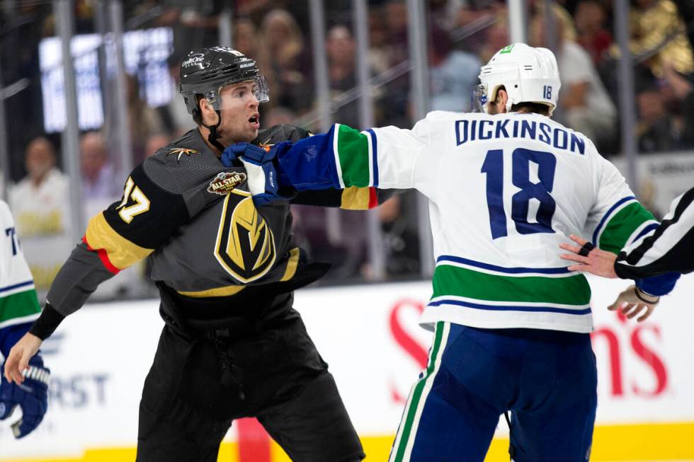 Golden Knights defenseman Ben Hutton (17) and Canucks center Jason Dickinson (18) fight during ...