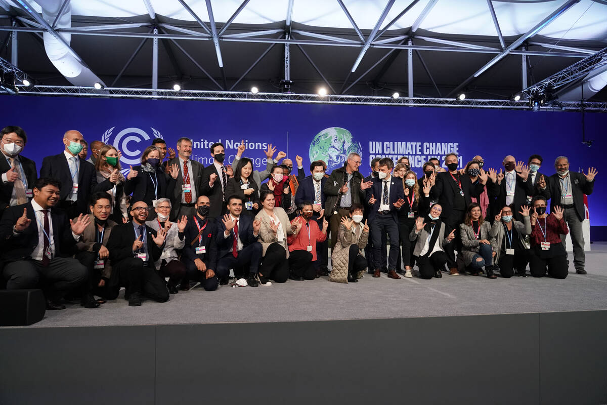 Delegates from different countries pose for a group photograph together on stage in the plenary ...