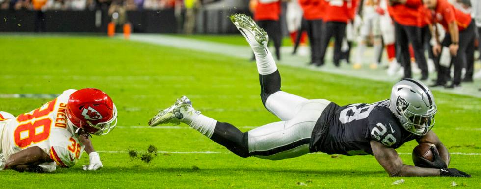 Raiders running back Josh Jacobs (28) dives for yards after taken down by Kansas City Chiefs co ...