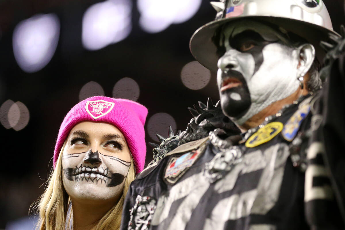 Fans watch players warmup before the start of an NFL football game between the Raiders and the ...