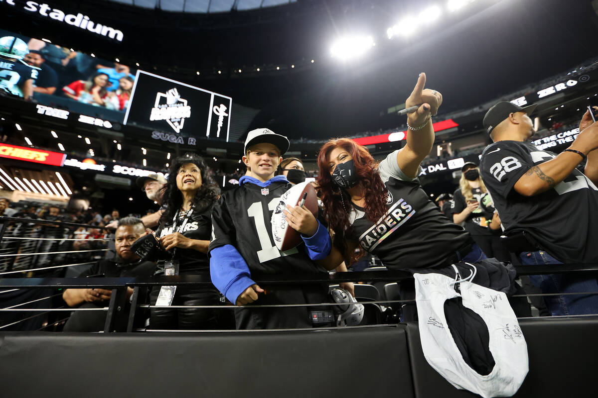 Fans watch players warmup before the start of an NFL football game between the Raiders and the ...