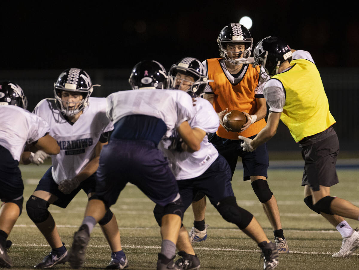 The Meadows High School quarterback Sean Gosse hands off the ball to John Mcgill, right, during ...
