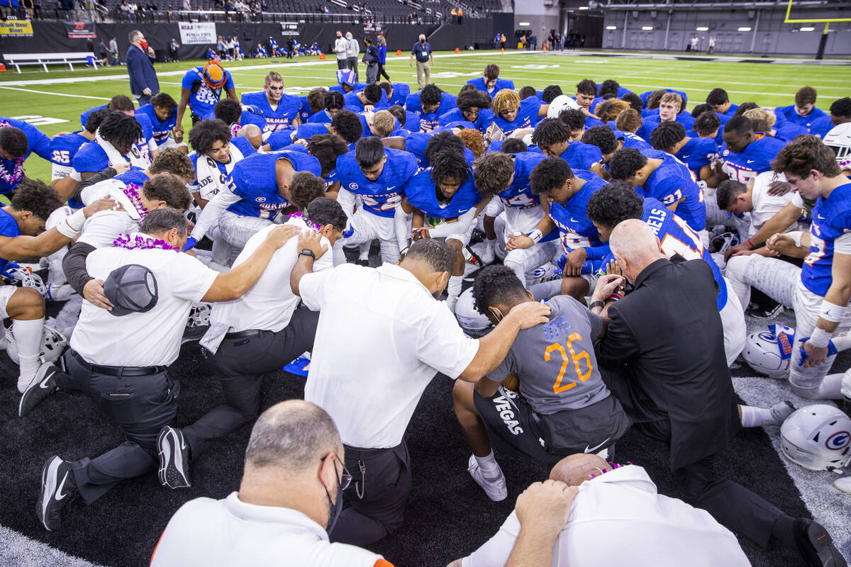Bishop Gorman head coach Brent Browner prays with his team after defeating McQueen 56-7 followi ...