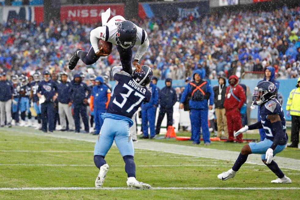 Houston Texans quarterback Tyrod Taylor, top, leaps over Tennessee Titans safety Amani Hooker ( ...