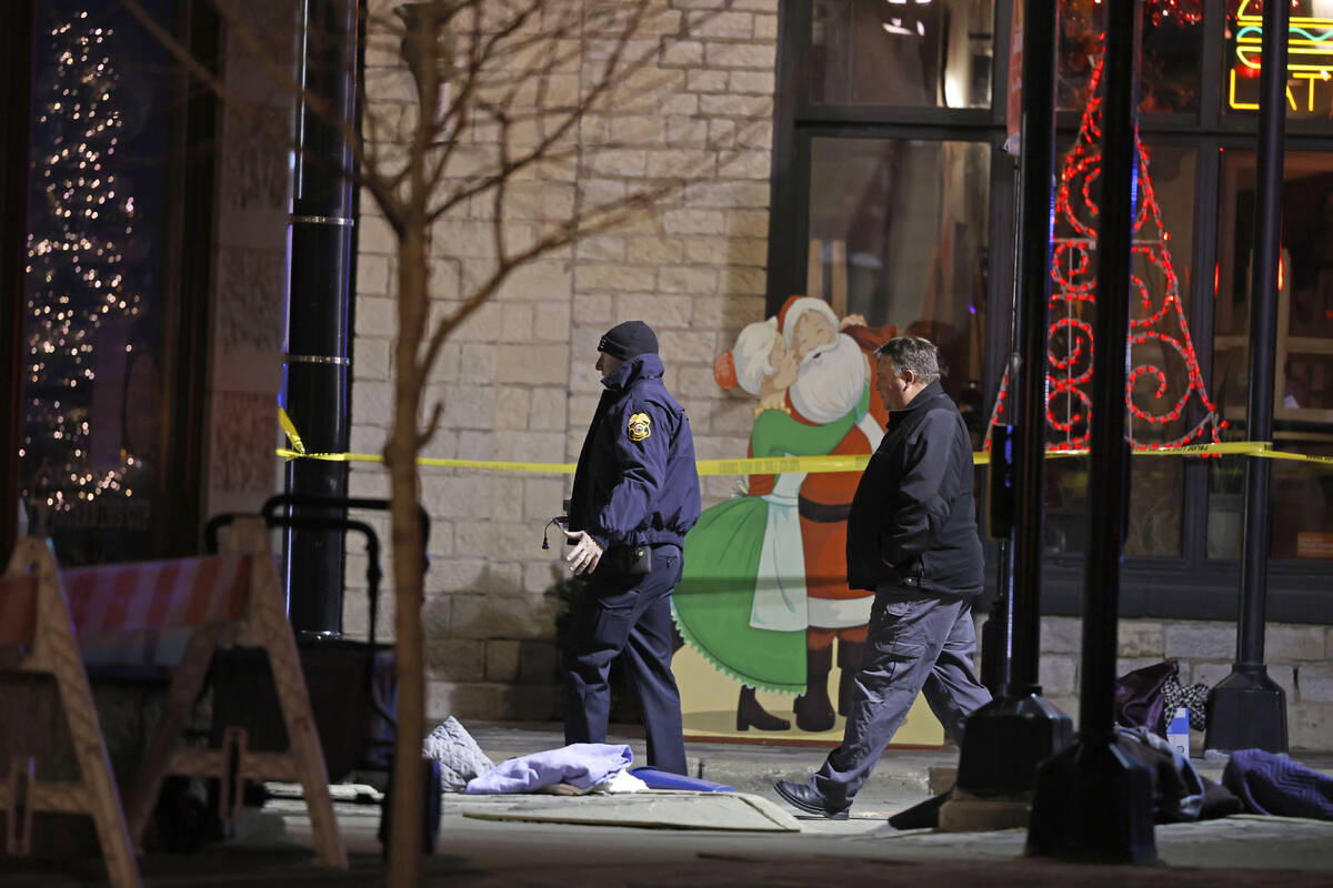 Holiday decorations frame police investigators in downtown Waukesha, Wis., after an SUV plowed ...