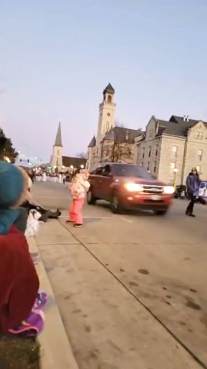 In this image taken from video an SUV speeds past a young girl and others attending a Christmas ...