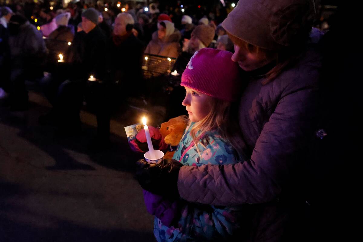 A child takes part in a candle light vigil in downtown Waukesha, Wis., Monday, Nov. 22, 2021 af ...