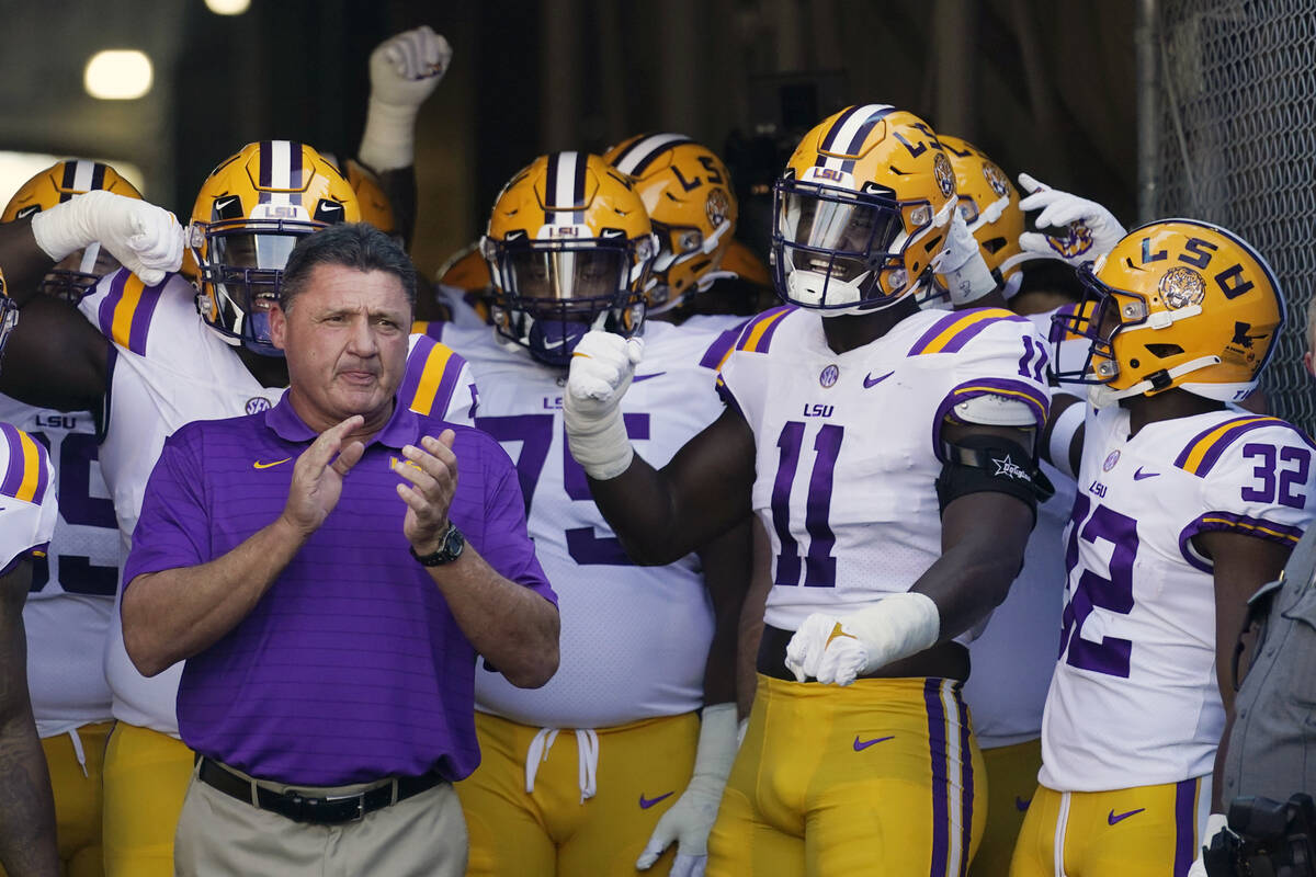 LSU coach Ed Orgeron, left, prepares to lead his team onto the field before an NCAA college foo ...