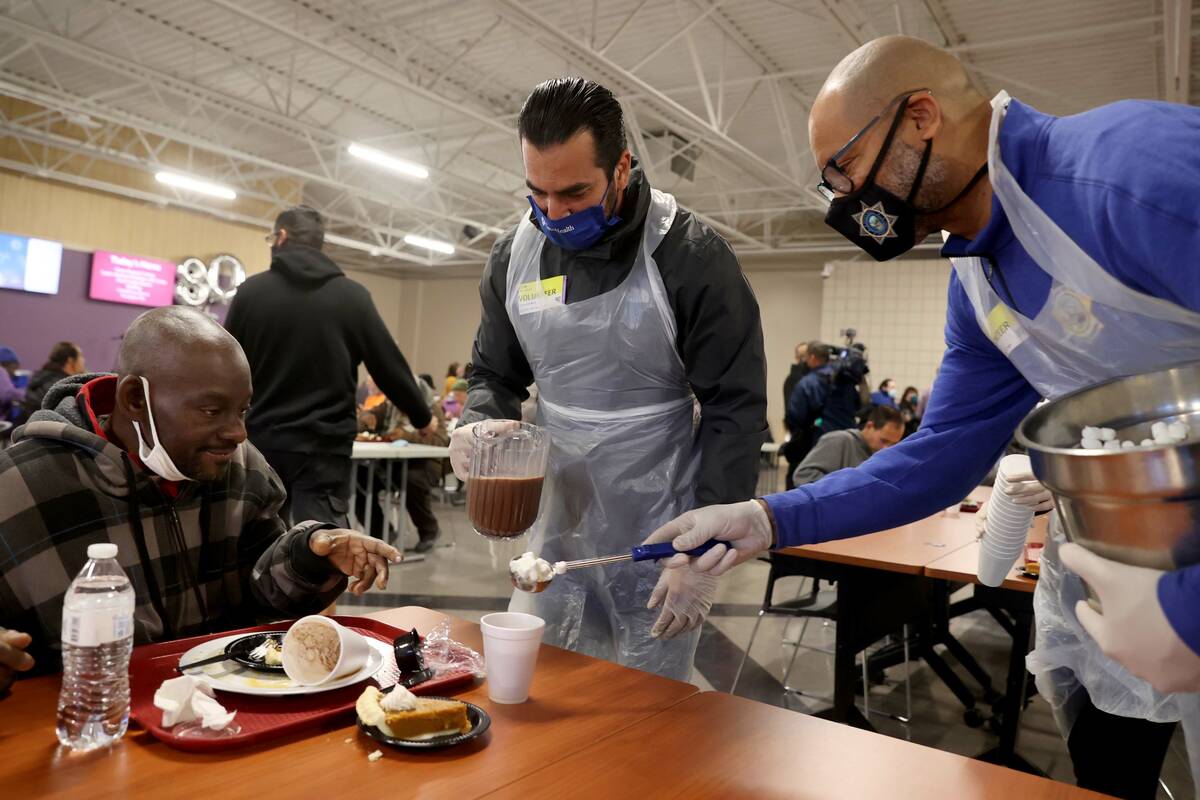 Ken Reed, 50, left, gets some hot chocolate from Attorney General Aaron Ford, right, and Ruben ...