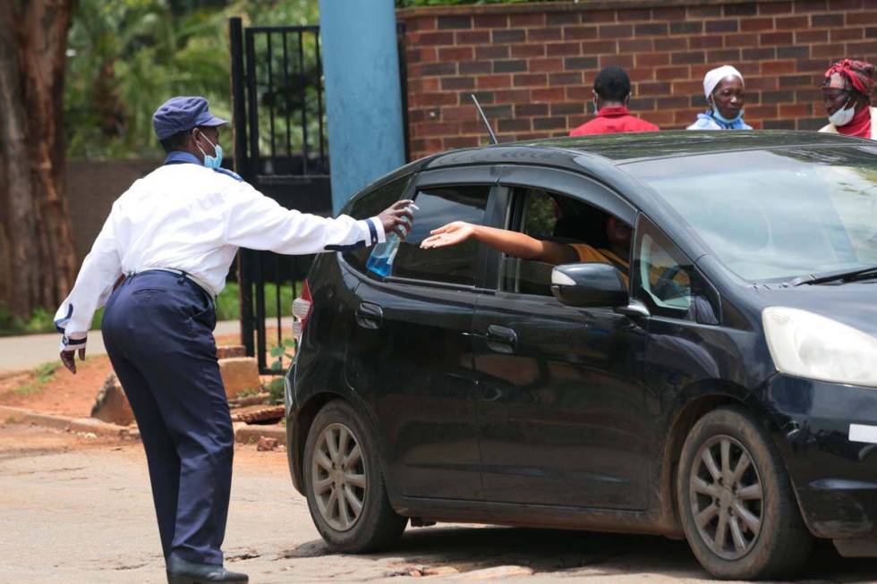 A security guard santizes a motorist's hands, at the entrance of a health facilty in Harare, Z ...