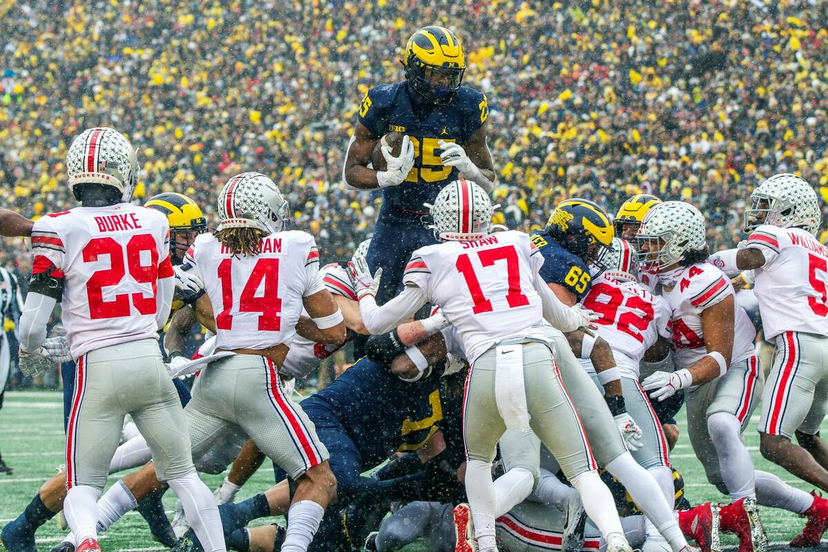 Michigan running back Hassan Haskins (25) leaps over Ohio State defenders for a touchdown in th ...
