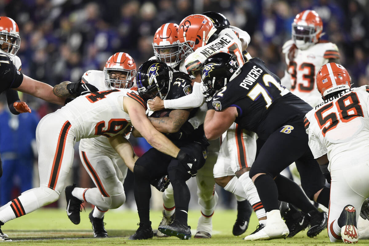 Baltimore Ravens running back Devonta Freeman (33) is stopped by a host of Cleveland Browns def ...