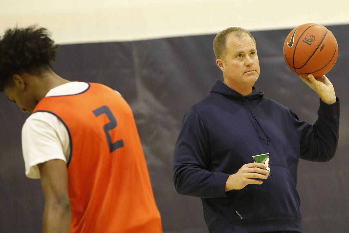 Bishop Gorman basketball head coach Grant Rice, right, holds a ball as Keenan Bey (2) walks by ...