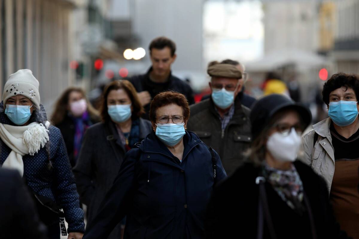 People wearing face masks to curb the spread of COVID-19 walk in downtown Lisbon, Portugal, on ...