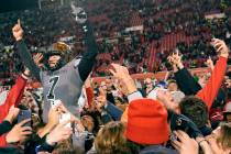 Utah quarterback Cameron Rising (7) celebrates with students who rushed the field following an ...