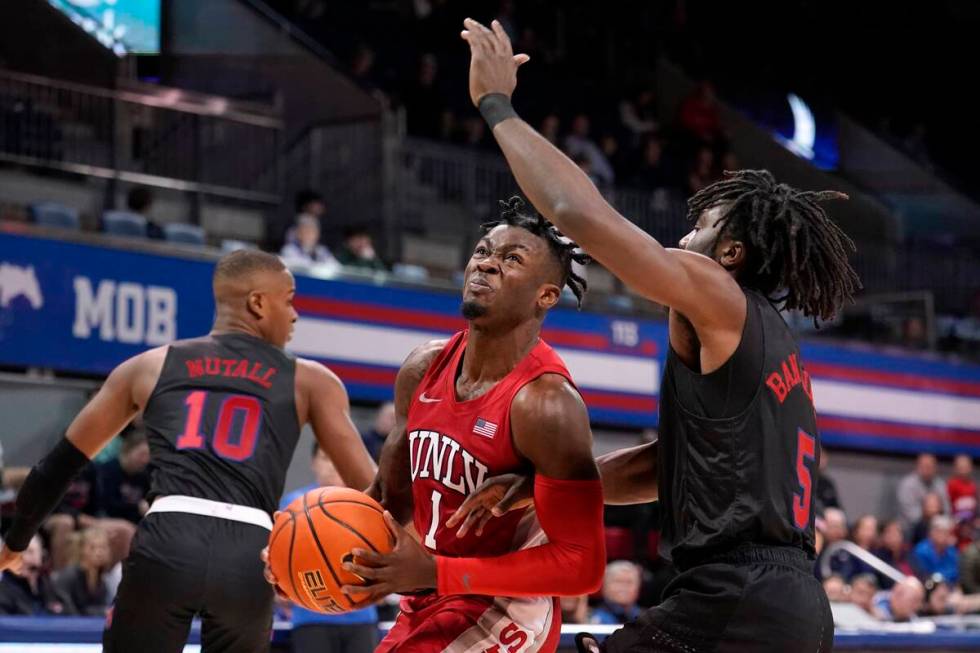 UNLV guard Michael Nuga (1) drives to the basket for a shot as SMU's Zach Nutall (10) and Emman ...