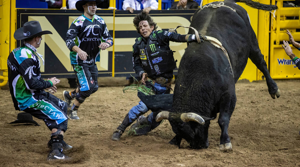 J.B. Mauney of Cotulla, Texas, is dragged by Johnny Thunder in Bull Riding as bullfighters move ...