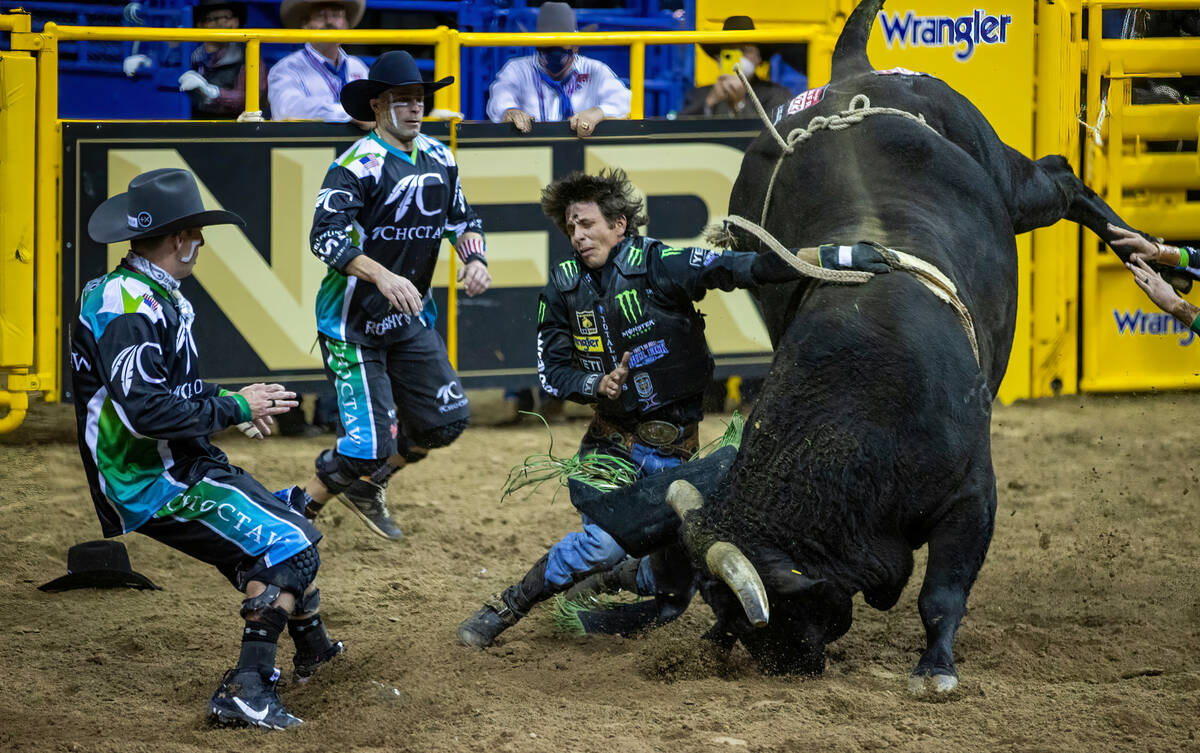 J.B. Mauney of Cotulla, Texas, is dragged by Johnny Thunder in Bull Riding as bullfighters move ...