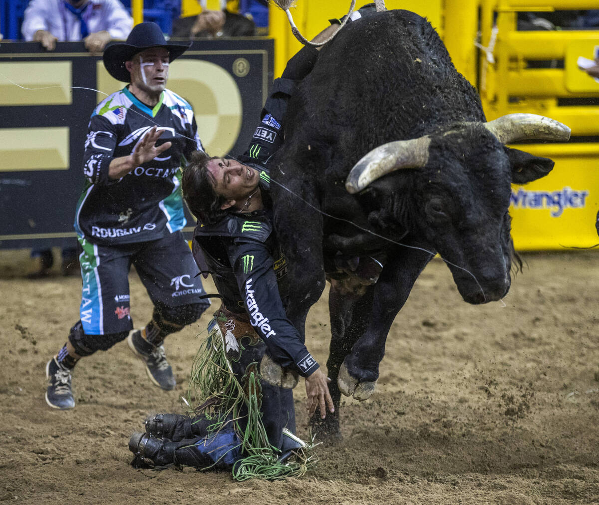 J.B. Mauney of Cotulla, Texas, is dragged by Johnny Thunder in Bull riding as a bullfighter mov ...
