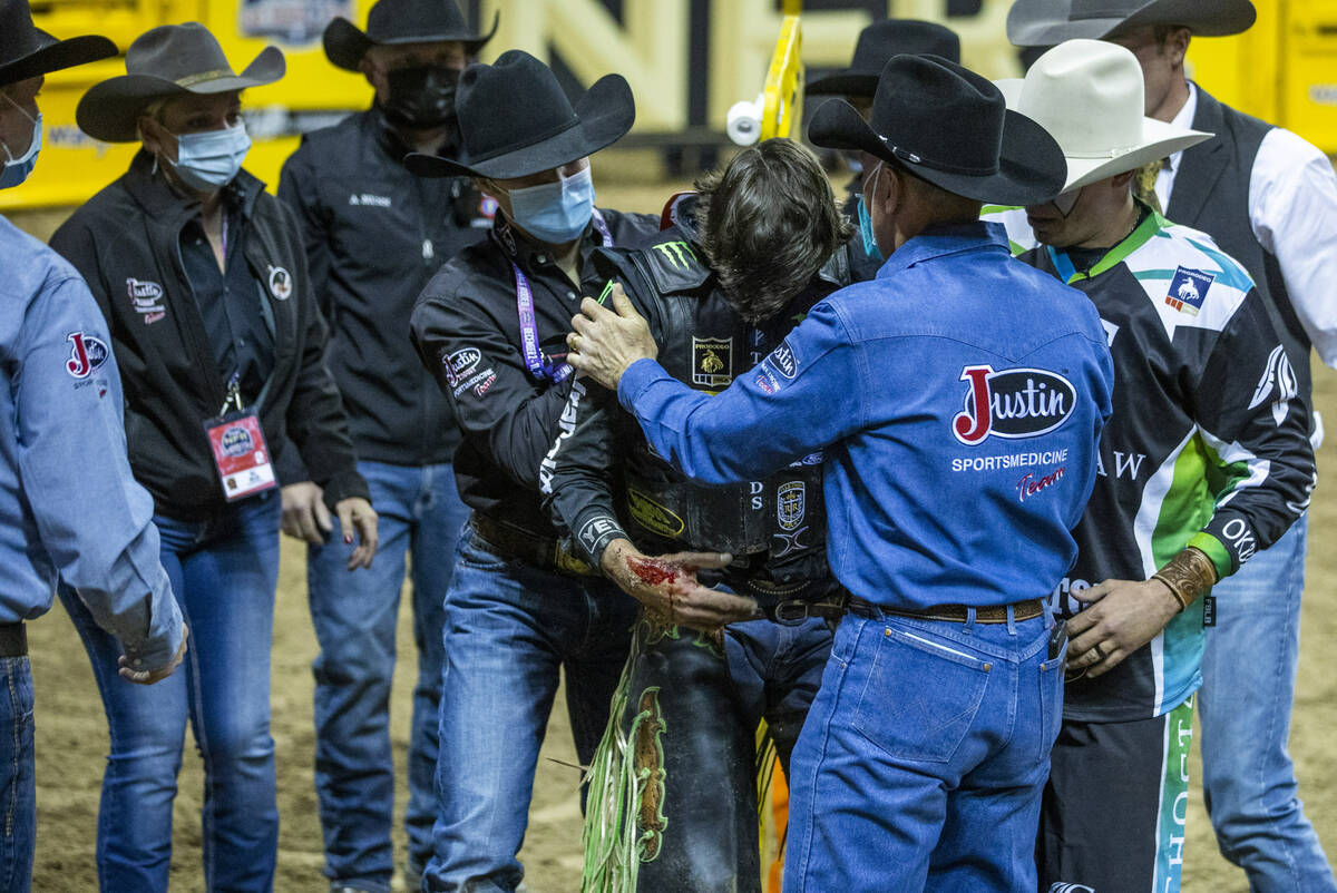 J.B. Mauney of Cotulla, Texas, is assisted from the arena after injured riding Johnny Thunder i ...