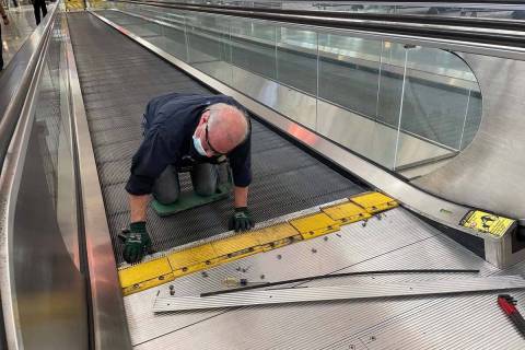 A worker preps a moving walkway at the E gate in Terminal 3 of McCarran International Airport. ...