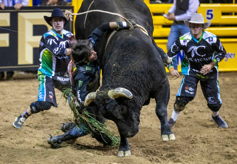 J.B. Mauney of Cotulla, TX., is dragged by Johnny Thunder in Bull Riding as bullfighters move i ...