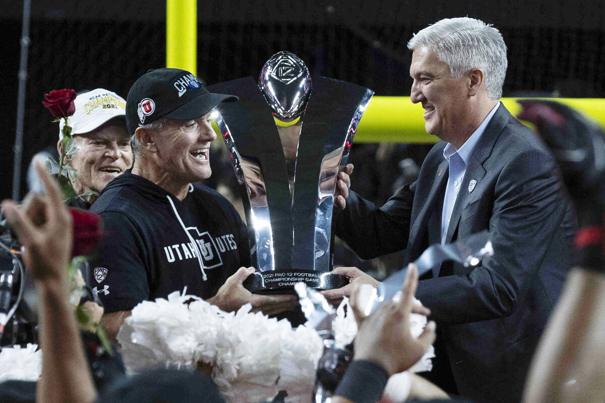 Pac-12 commissioner George Kliavkoff, right, presents the championship trophy to Utah Utes head ...