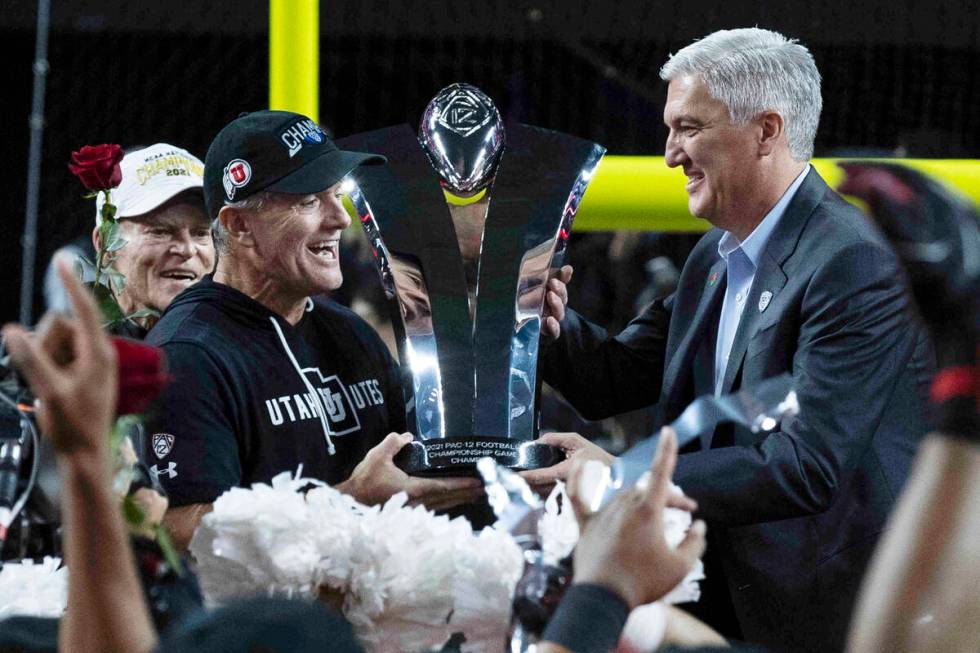 Pac-12 commissioner George Kliavkoff, right, presents the championship trophy to Utah Utes head ...