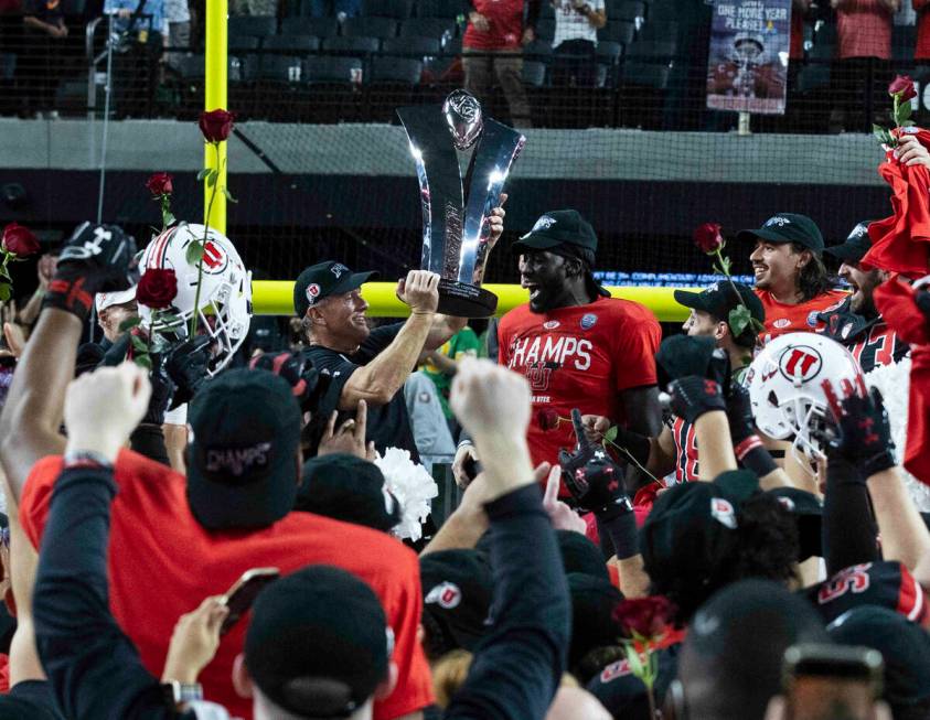 Utah Utes head coach Kyle Whittingham, left, raises the championship trophy as he celebrates wi ...