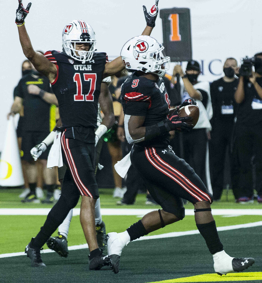 Utah Utes running back Tavion Thomas (9) scores a touchdown as wide receiver Devaughn Vele (17) ...