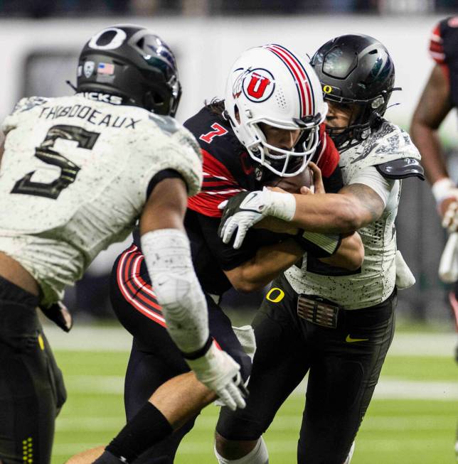 Utah Utes quarterback Cameron Rising (7) sandwiched between Oregon Ducks defenders, including d ...