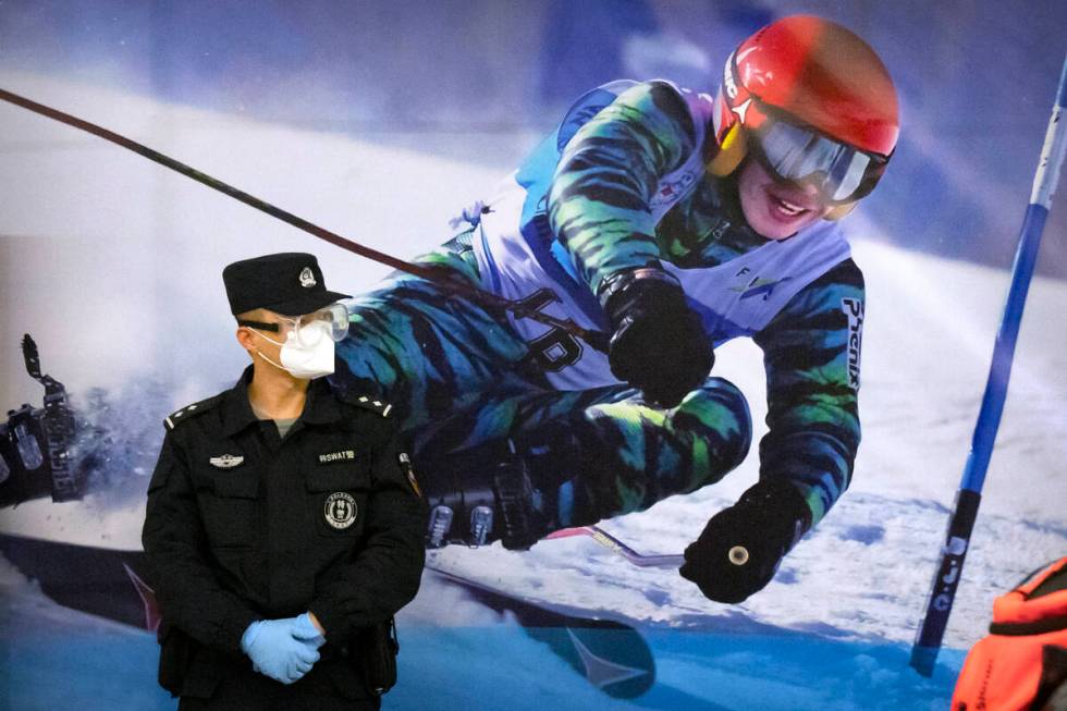 FILE - A police officer wearing a face mask and goggles to protect against COVID-19, stands nea ...