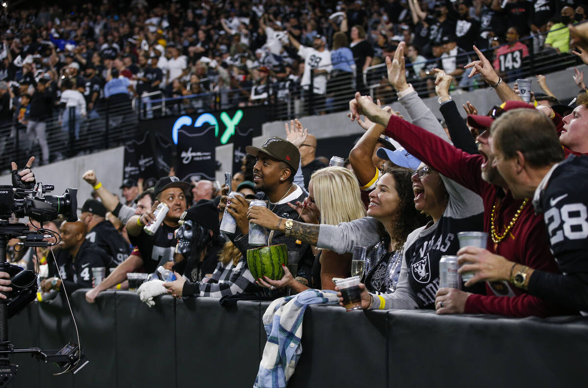 Football fans cheer for the camera at the Wynn Field Club during an NFL game between the Raider ...