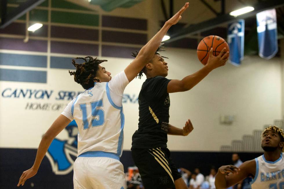 Spring Valley guard Randy Nance (5) attempts a point while Canyon Springs forward Jalen Foy (15 ...