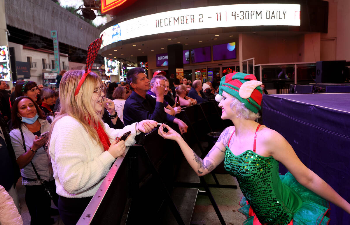 Enchanted Elf Jasmine Valencia gives a candy cane to Maya Watts of Las Vegas at the 3rd Street ...