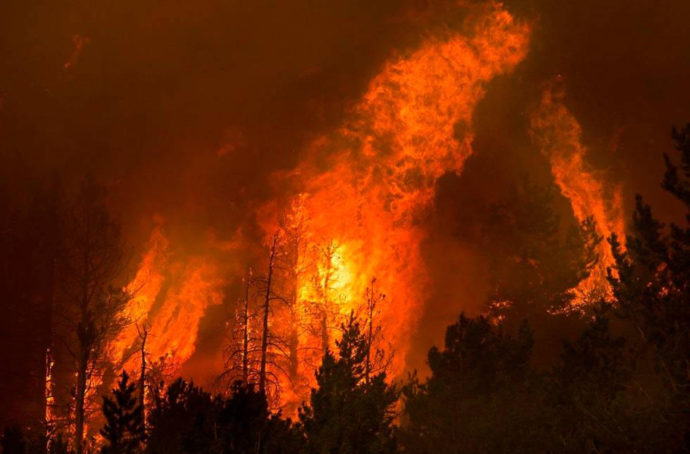 Flames erupt in trees on a nearby ridge above Caples Lake as the Caldor Fire continues to burn ...