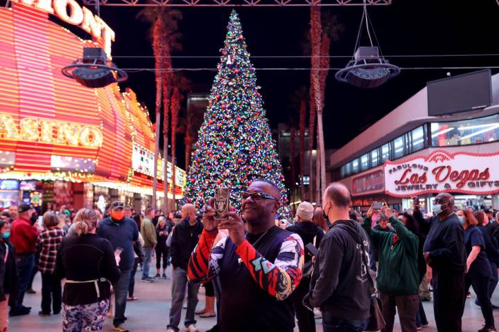 People take photos during the Christmas tree lighting ceremony at the 3rd Street Stage at the F ...