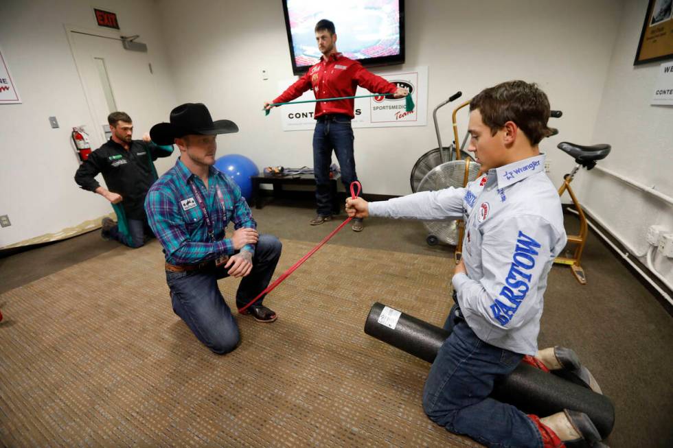 Former rodeo competitor Doug Champion, left, does physical therapy for competitor Clayton Biglo ...