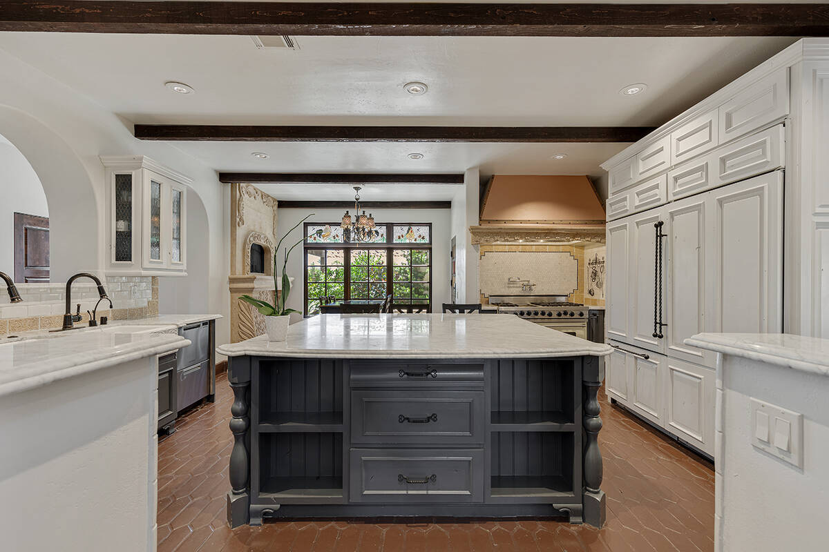 The kitchen features an oversized center island, double apron-front sinks, separate prep sink a ...